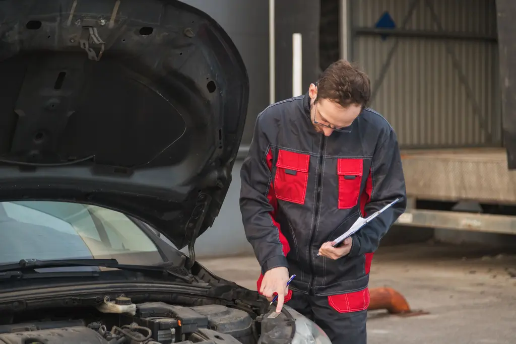 Mechanic inspecting a car and reviewing a vehicle repair order